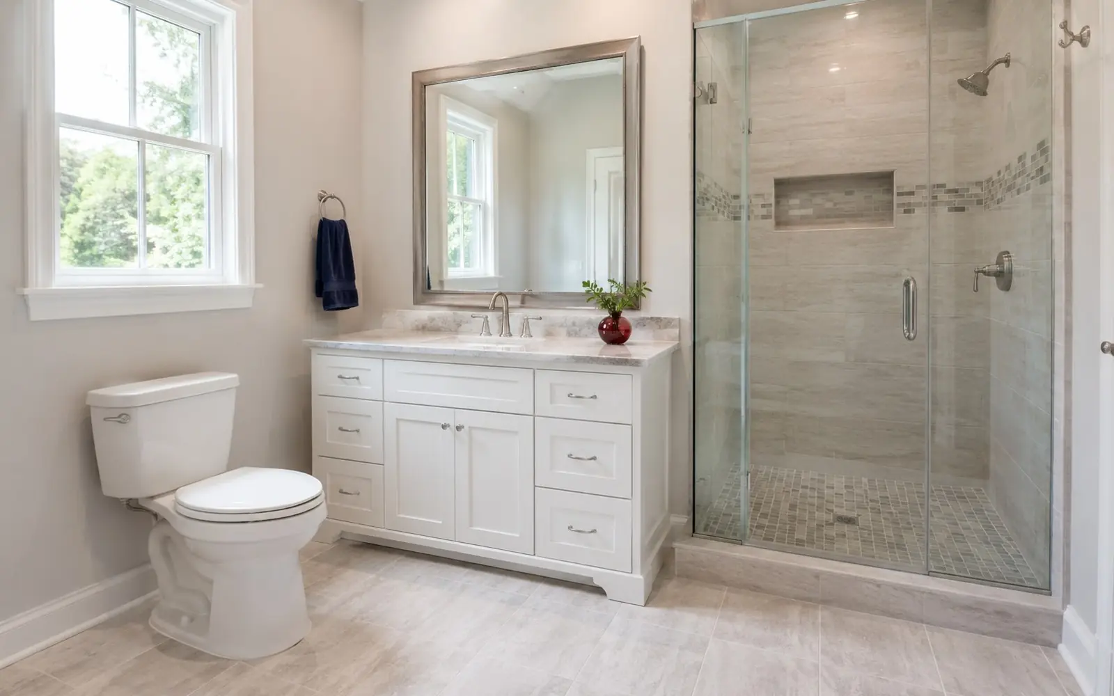 Wide view of a full bathroom design: toilet, and separately a floating vanity clearly mounted to the wall with a visible concealed support bracket/ledger beneath it (securely wall-hung, not levitating), framed mirror, tiled shower, cohesive palette