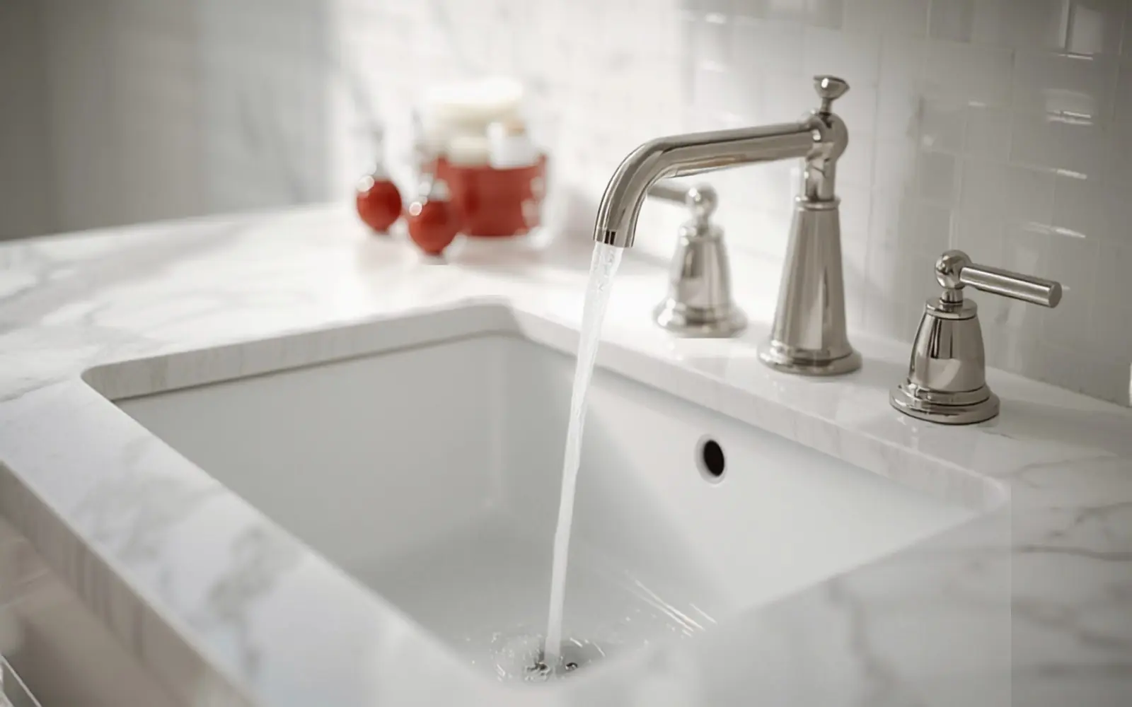 Close on a new brushed-nickel widespread faucet on an undermount sink, water running
