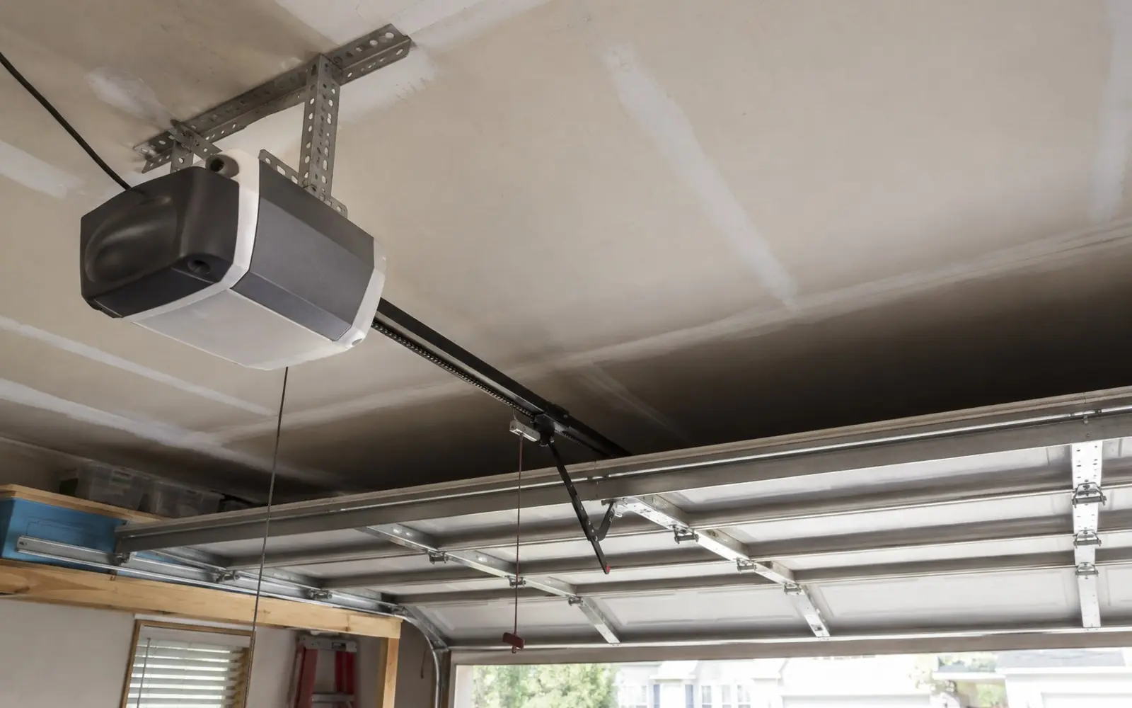 A ceiling-mounted chain drive garage door opener with its rail and trolley, photographed from below inside a domestic garage.