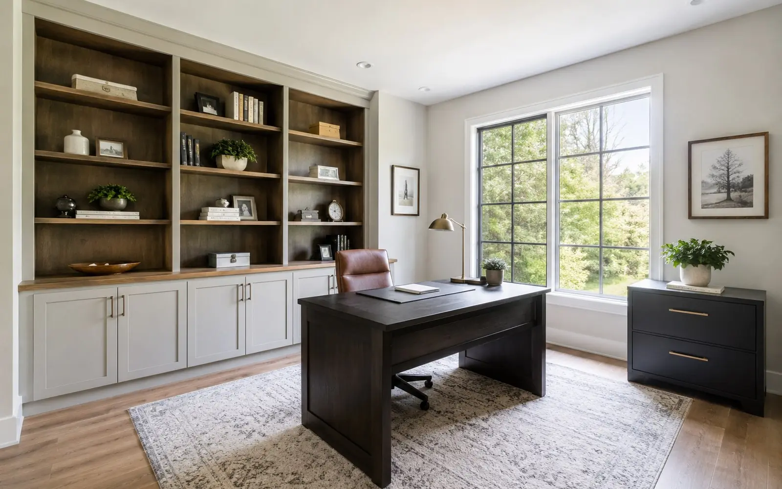 A home office wall lined with built-in cabinetry, open upper shelves above a run of closed base cabinets, and a two-drawer lateral filing cabinet standing beside a desk.
