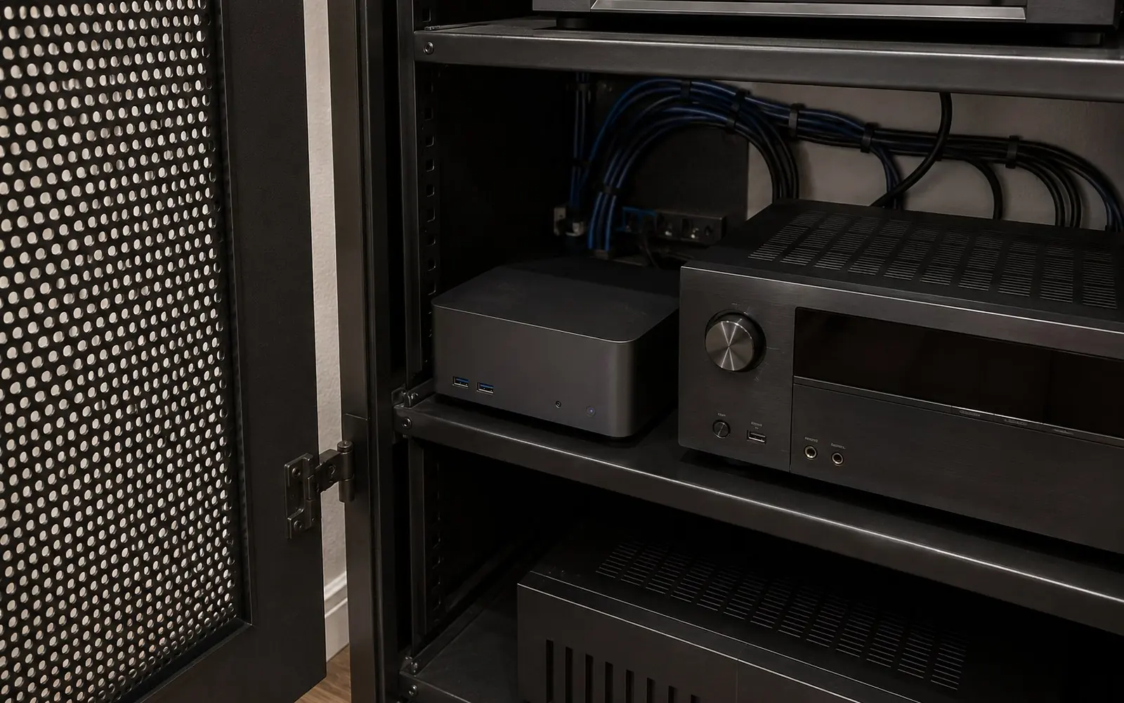 A small silent computer sitting on a rack shelf beside an AV receiver, with cables routed neatly behind a ventilated equipment closet door.