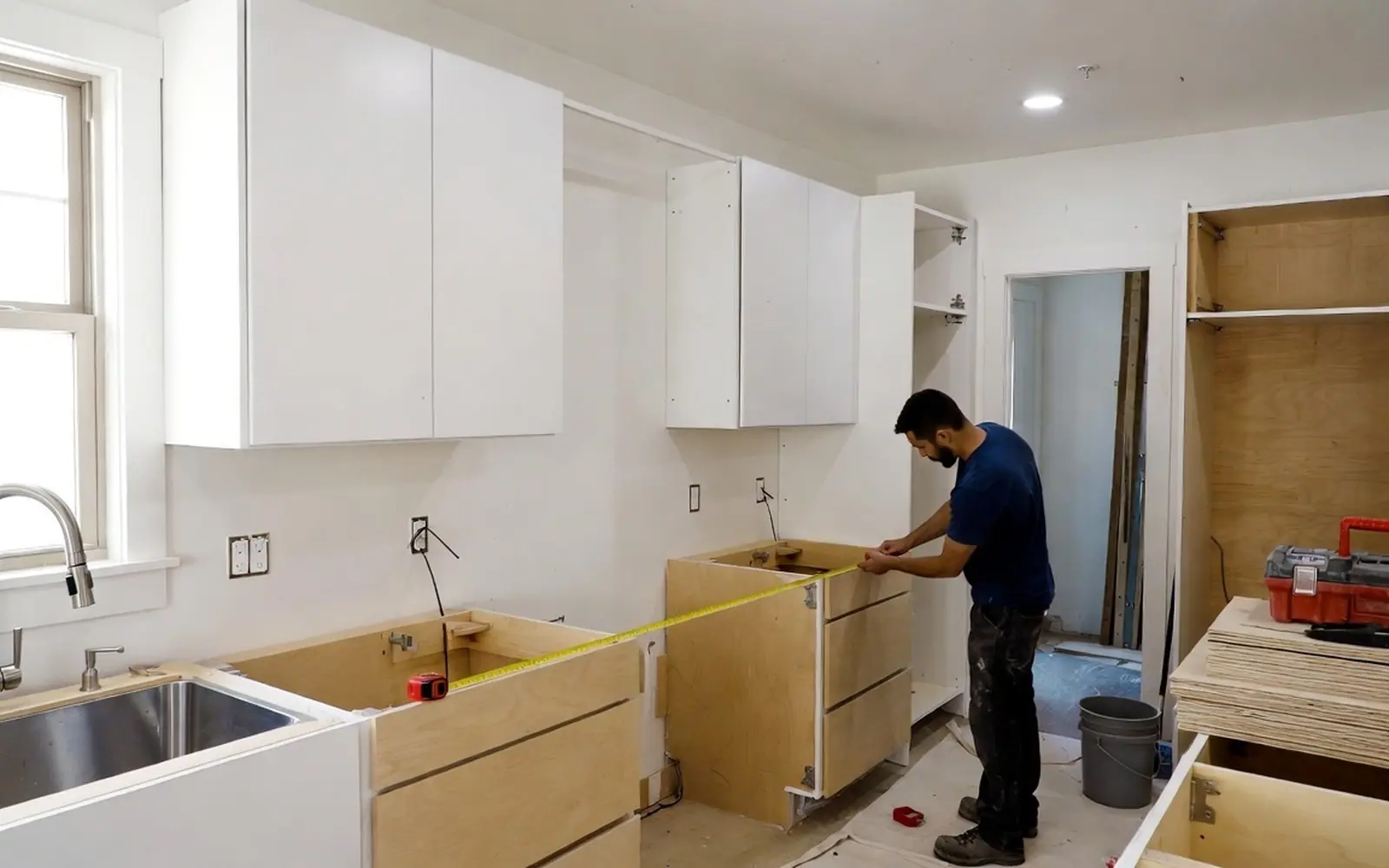 Kitchen mid-remodel: new cabinets in, counters templated, contractor measuring